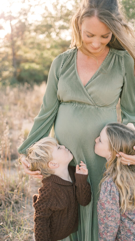 motherhood portrait of pregnant mom being kissed on the belly by son and daughter