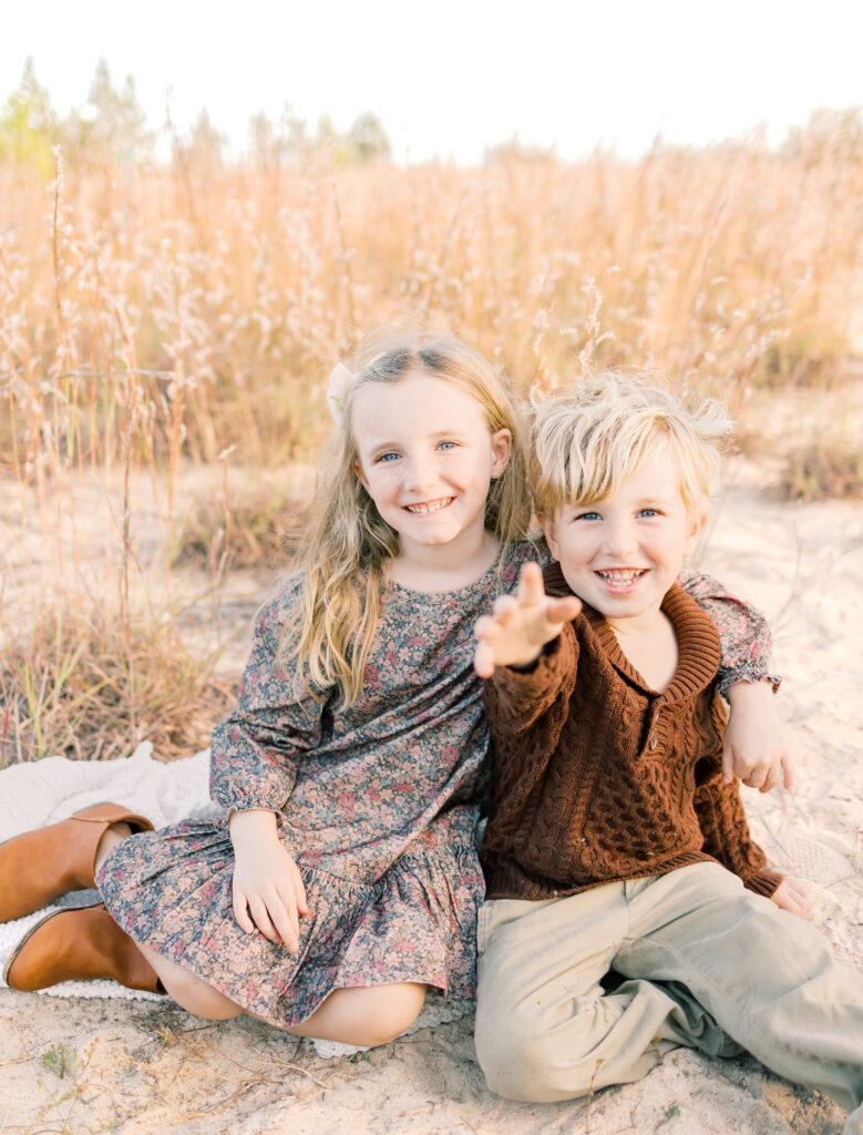 siblings sitting at sandy park smiling and hugging