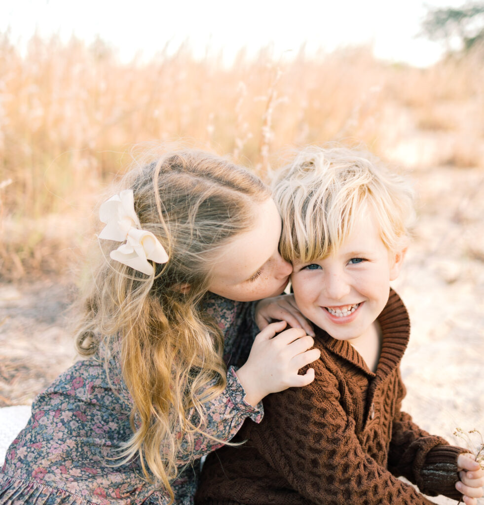 sister kissing brother on the cheek while he is laughing