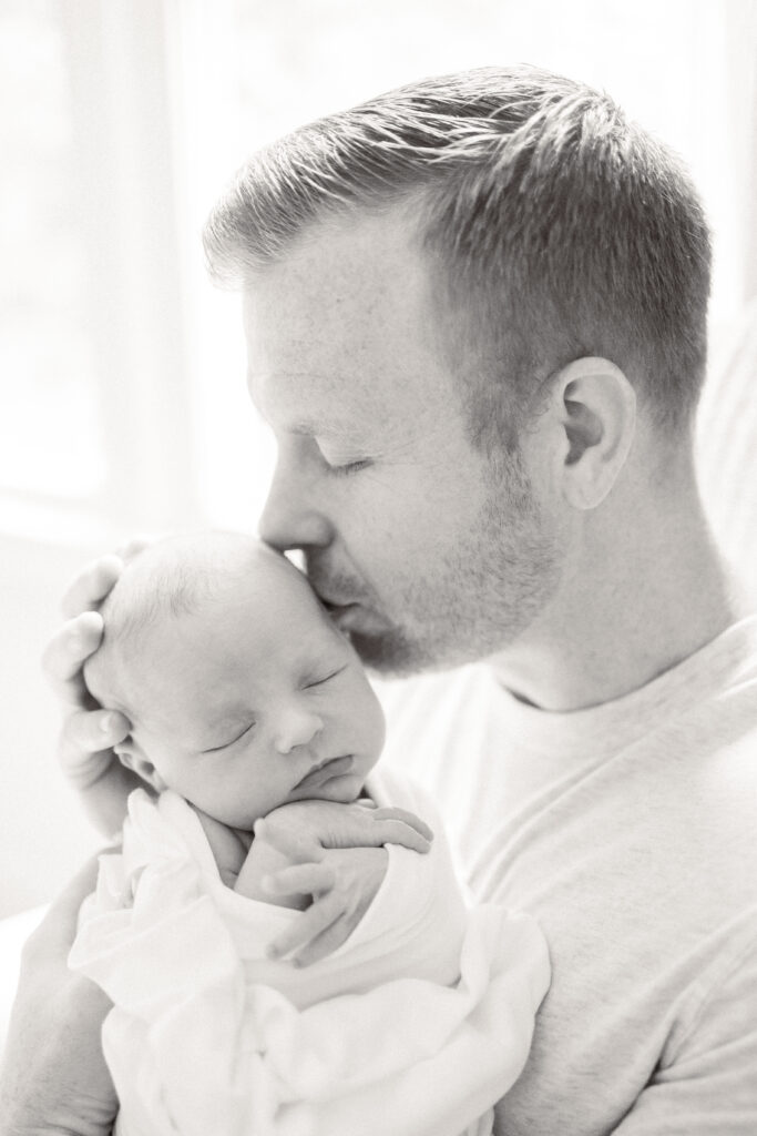 dad holding newborn baby girl during lifestyle newborn photos in their nursery 