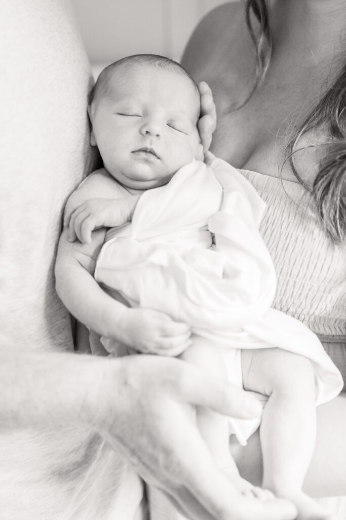 black and white image of newborn baby girl swaddled in white swaddle during newborn photos in virginia beach