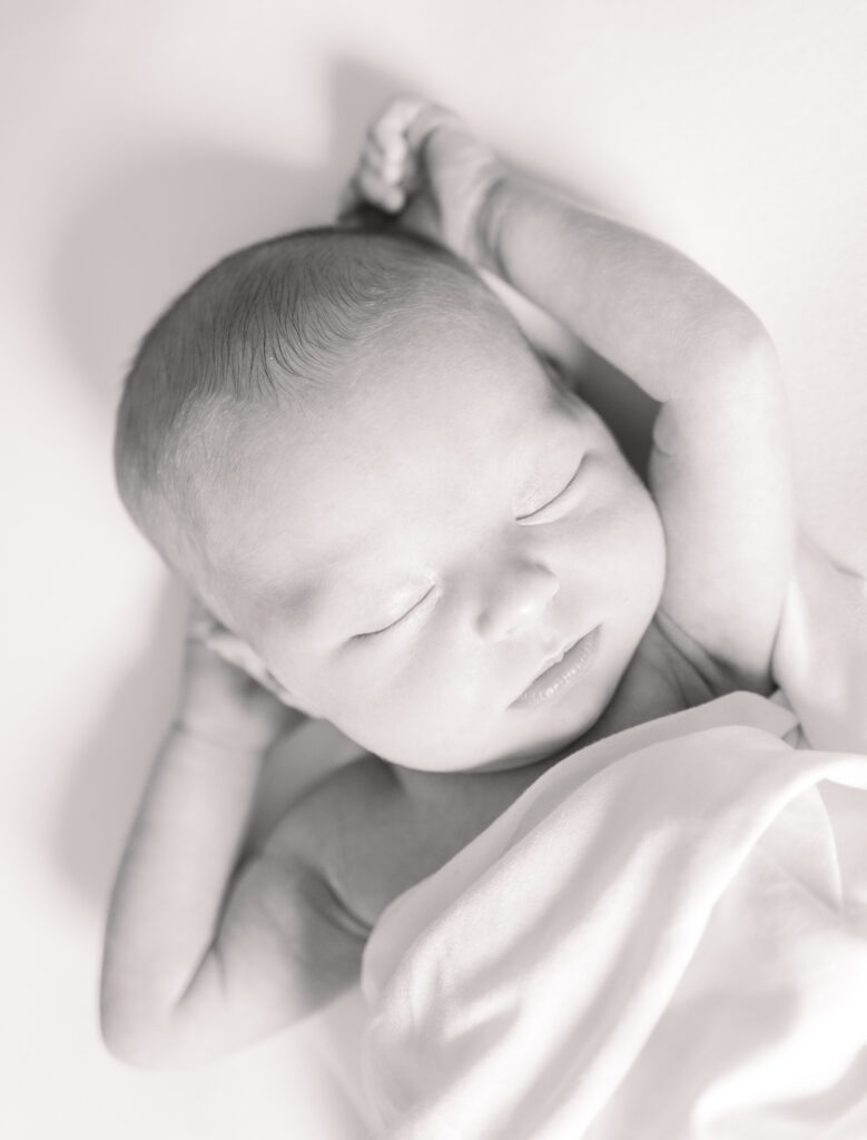 newborn baby girl stretching in white swaddle during newborn photos in virginia beach