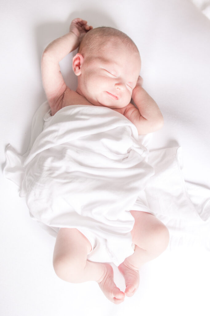 newborn baby girl stretching and smiling during newborn photo session in virginia beach 