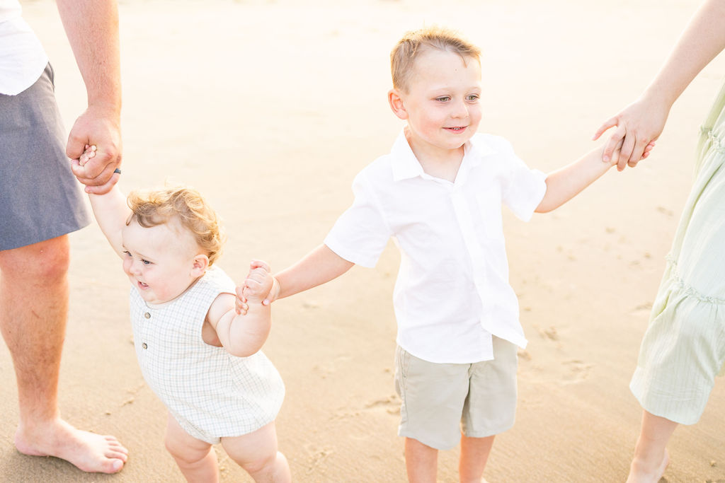 candid moment caught of two brothers holding hands during virginia beach family photos