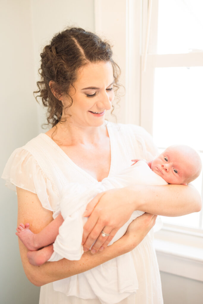 mom holding her brand new baby boy who is wide awake during their in home newborn photos