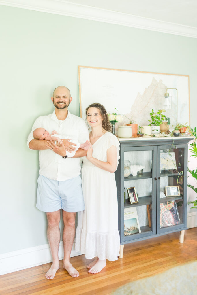 first time mom and dad smiling at the camera during their at home newborn photos in virginia beach