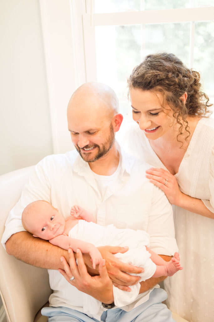 first time mother and father snuggling with baby during at home newborn photos