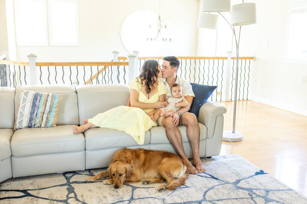 family of 3 snuggling on the couch during lifestyle family photos at home in moyock, nc. 