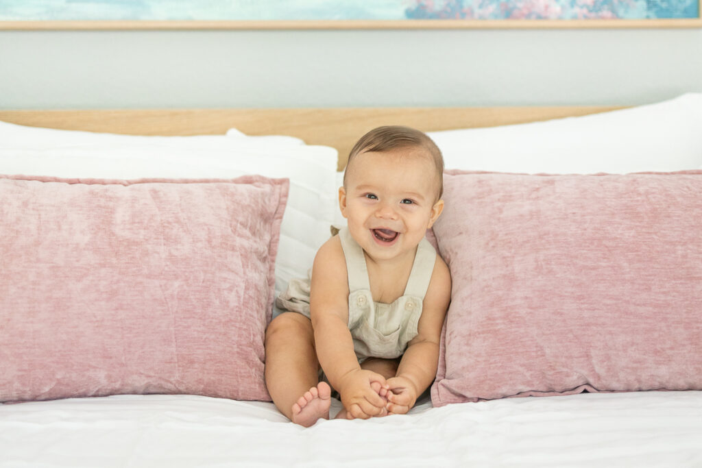 7 month old baby boy smiling during family photos on the bed