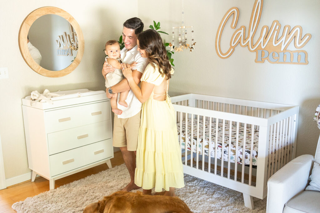 parents smiling at their baby boy in his nursery during at home family photos