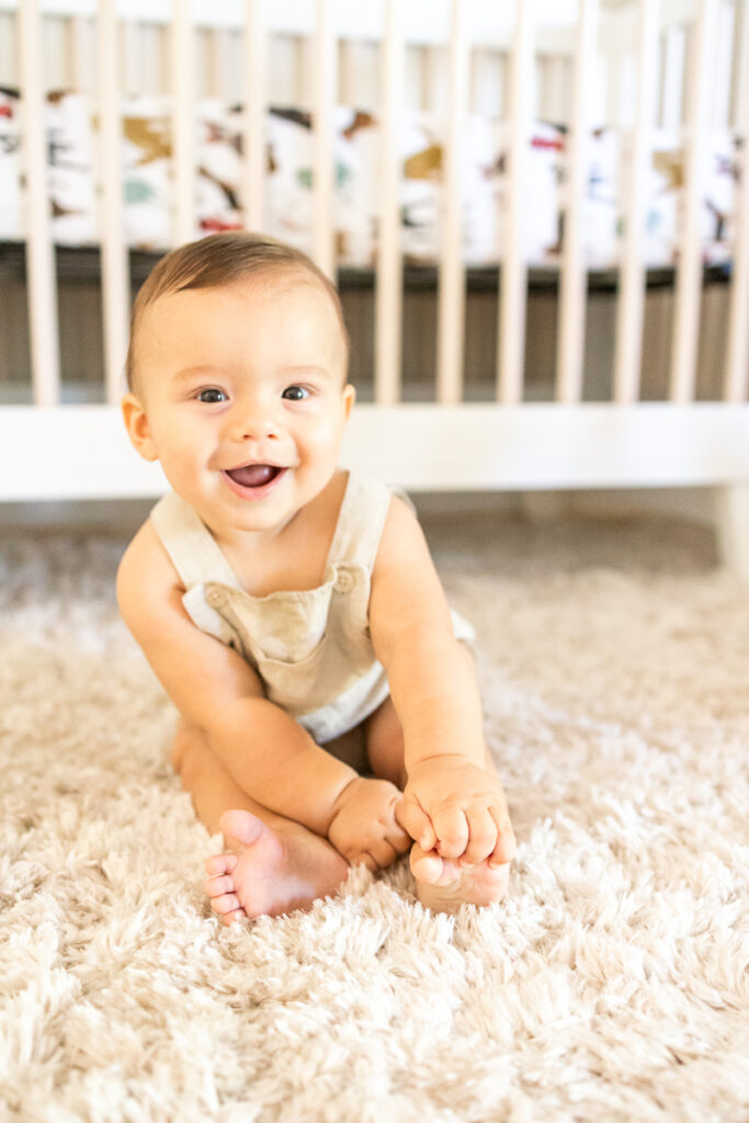 precious smiling 7 month old baby boy smiling for family photos in his nursery