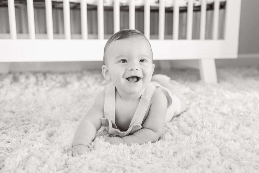 black and white image of 7 month old baby boy smiling during tummy time