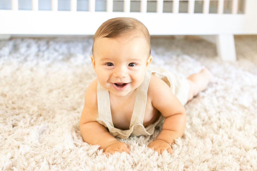 7 month old baby boy in his nursery smiling during lifestyle family photos