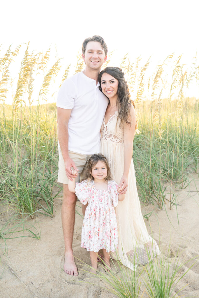 family of 3 smiling for classic portrait on the beach