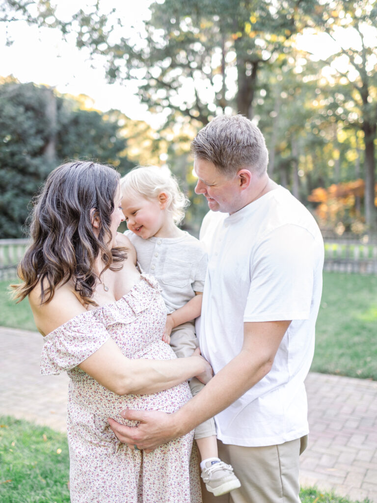 adorable candid photo of pregnant mother holding laughing son while being snuggled by his dad during maternity photos