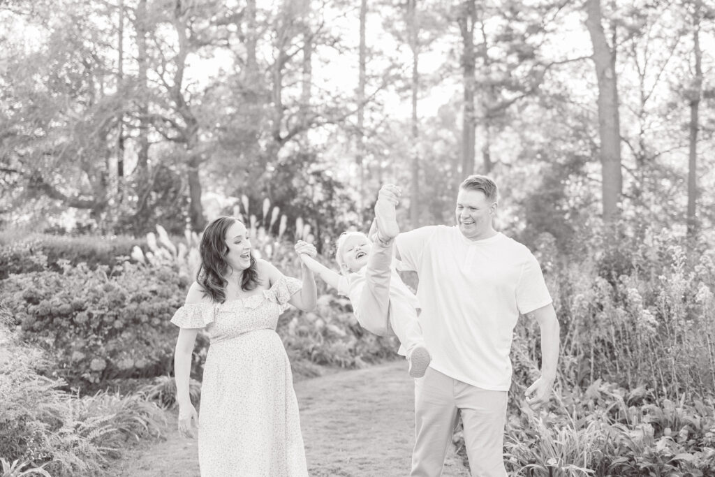 black and white maternity and family photo of family of 3 playing in botanical gardens