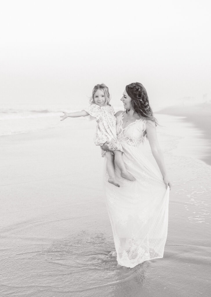 mom twirling and dancing with her toddler daugther on her hip during summer family photos