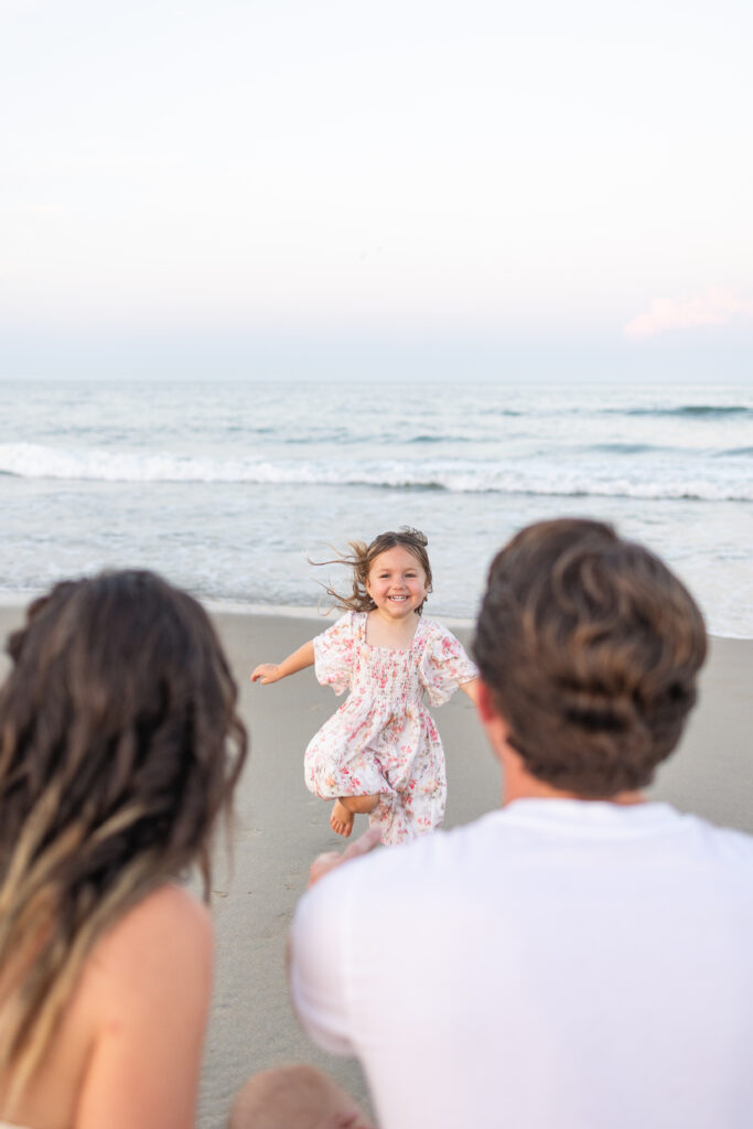 joyful family photo of toddler girl racing to parents during family photos