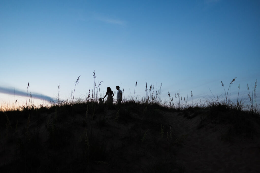 sunset image of family of 3 walking on the dunes at sunset in virginia beach