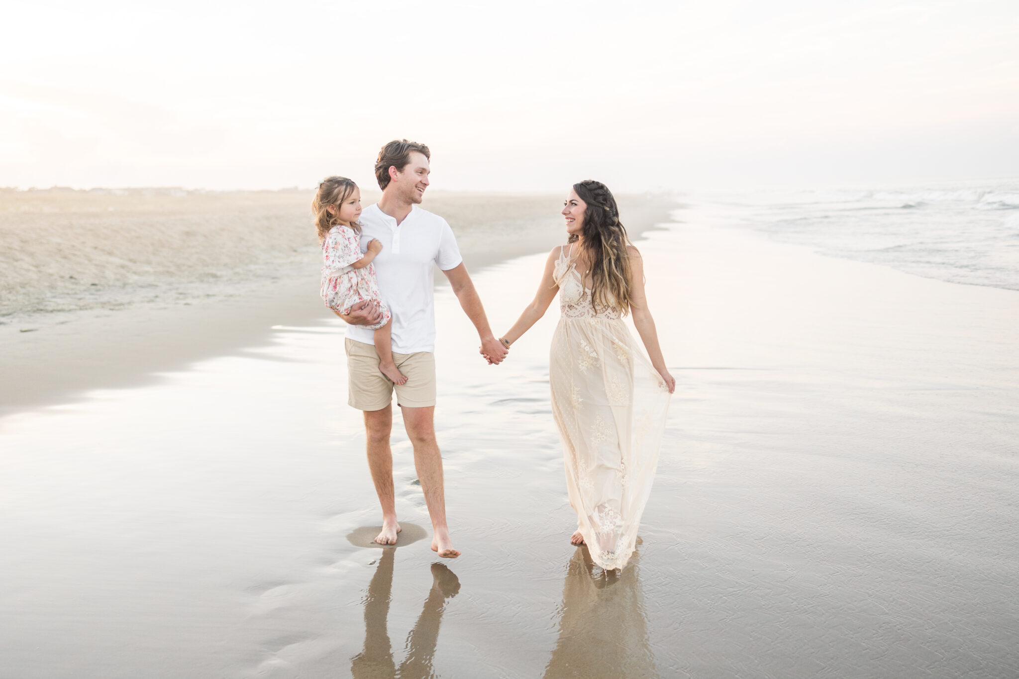 family walking near the edge of the water during sunset photos in virginia beach