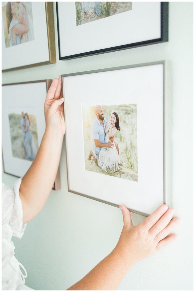 custom framed portraits being hung on a wall by virginia beach family photographer chelsey kraus photography