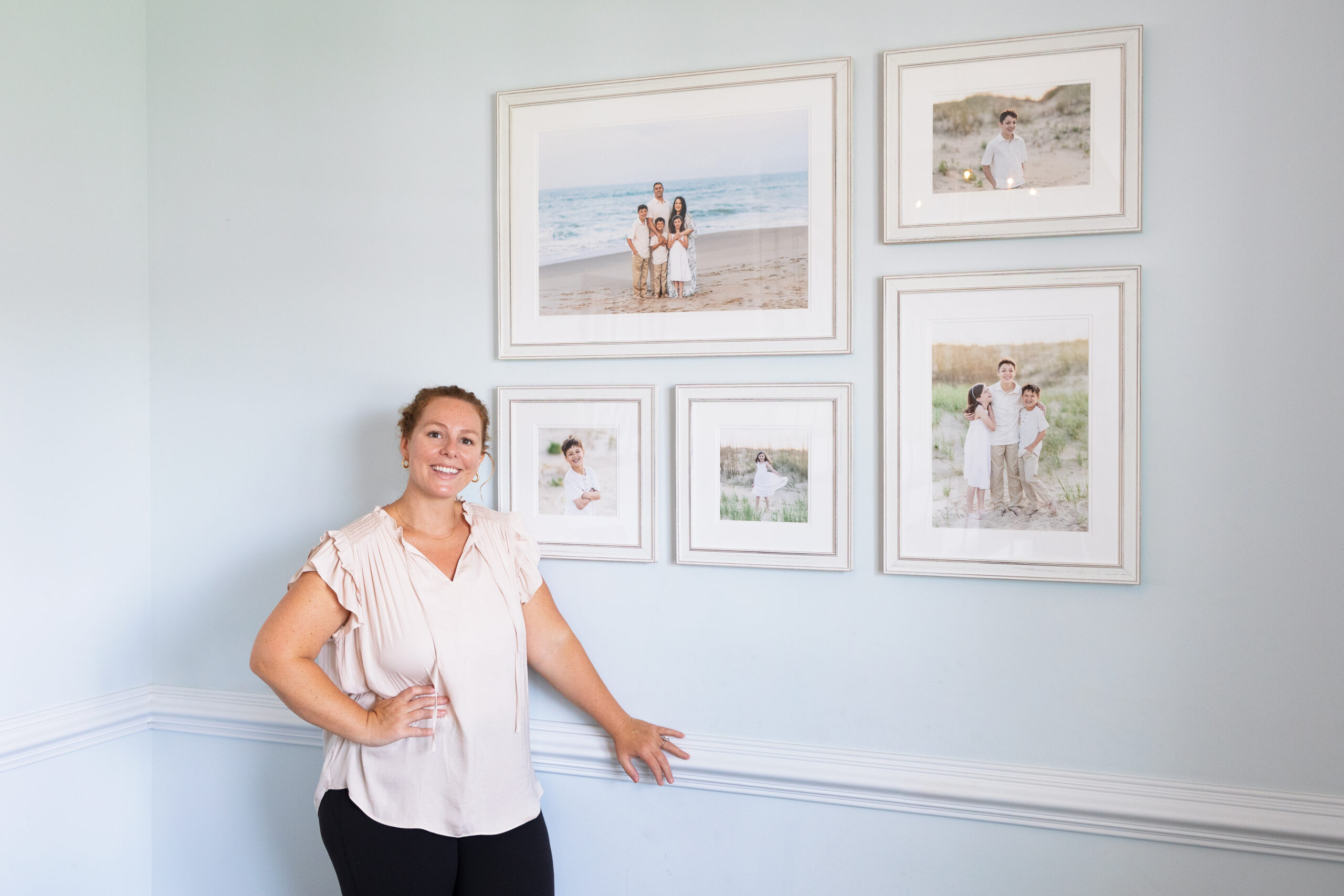 full service photographer posing by family photo gallery wall installed by chelsey kraus photography