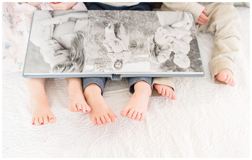 3 toddlers sitting and looking at heirloom family photo album 