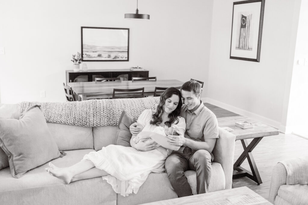 family photo of mom and dad cuddling newborn baby girl during relaxed and cozy newborn photos at home