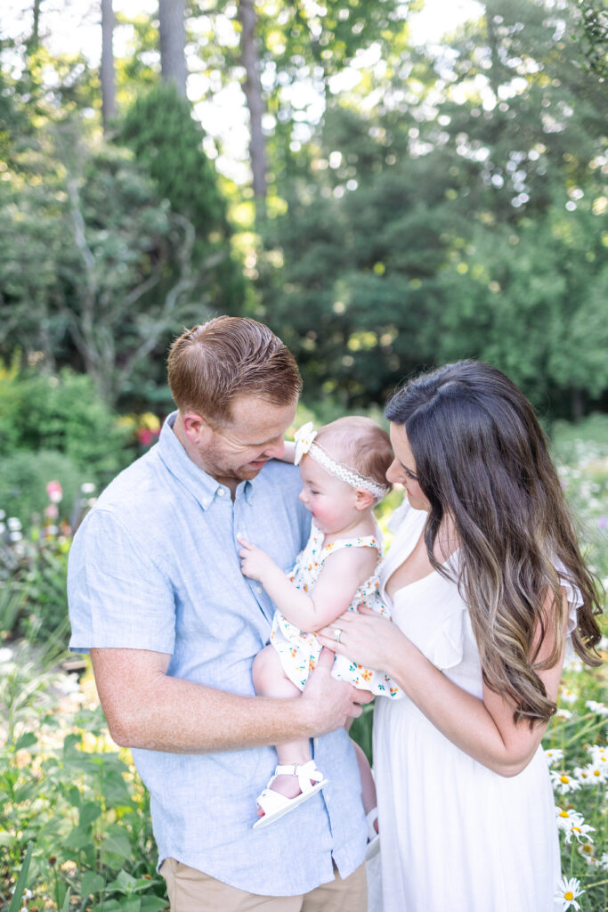 family of 3 hugging during their family photos at the Norfolk Botanical Gardens in Norfolk, Virginia.