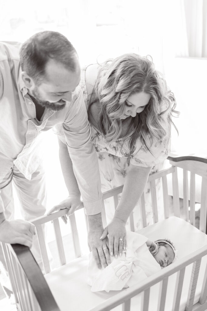 mom and dad looking down at their newborn baby girl during newborn photos at home