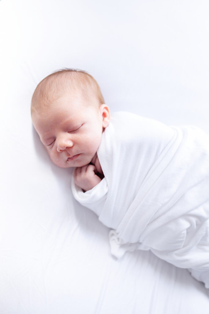 Newborn Photos In Virginia Beach featuring a swaddled picture of a baby sleeping