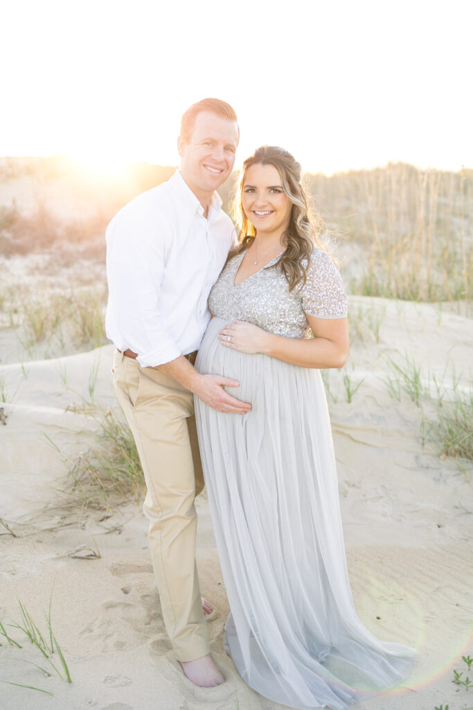 Beautiful pregnant woman and husband posing at the beach