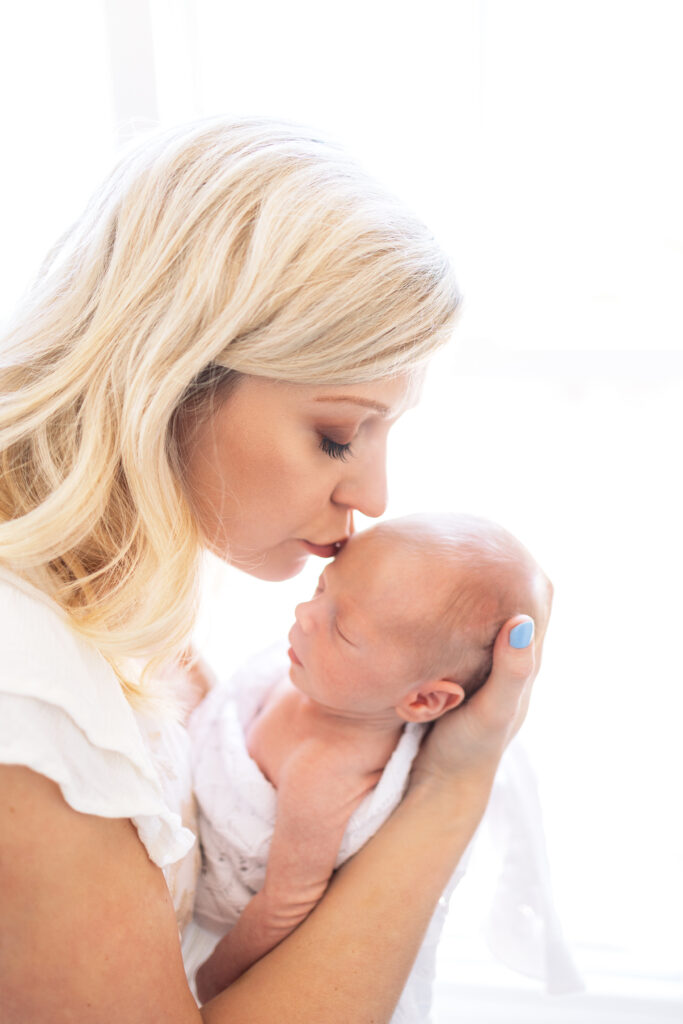 Are you considering documenting baby's first year?  Virignia Beach newborn photographer captures a mom kissing her baby